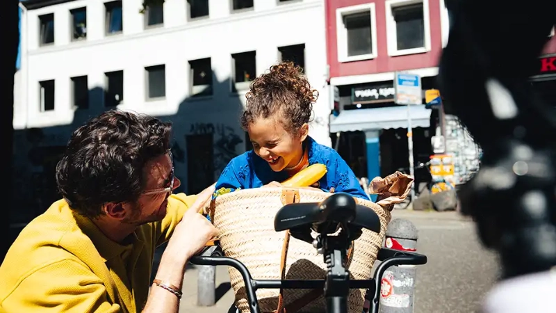 Vater mit Tochter und vollgepacktem Lastenrad