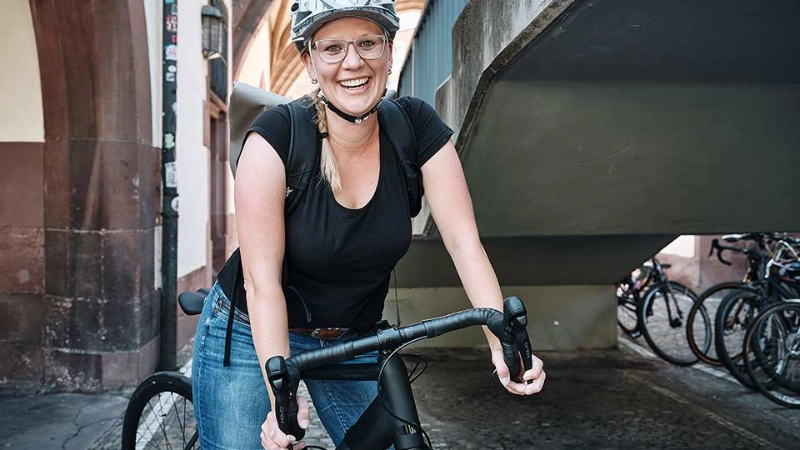 Eine lachende Frau auf ihrem schwarzen Fahrrad