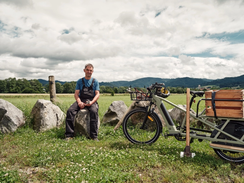 Landwirt sitzt neben Longtail auf Stein und guckt Landwirt sitzt neben Longtail auf Stein und guckt